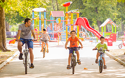 A father and his children ride their bikes through a park in Bulgaria.