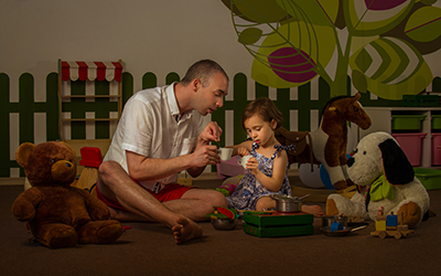 A father and his daughter have a tea party while surrounded my stuffed animal friends in Bulgaria.