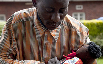 A man in a fatherhood training class holds a baby doll in his arms.