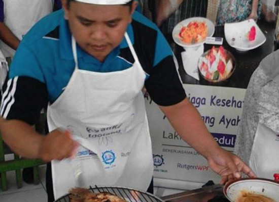 An action shot of a participant from "Cooking Competition for Dads" in indonesia grilling a piece of chicken.