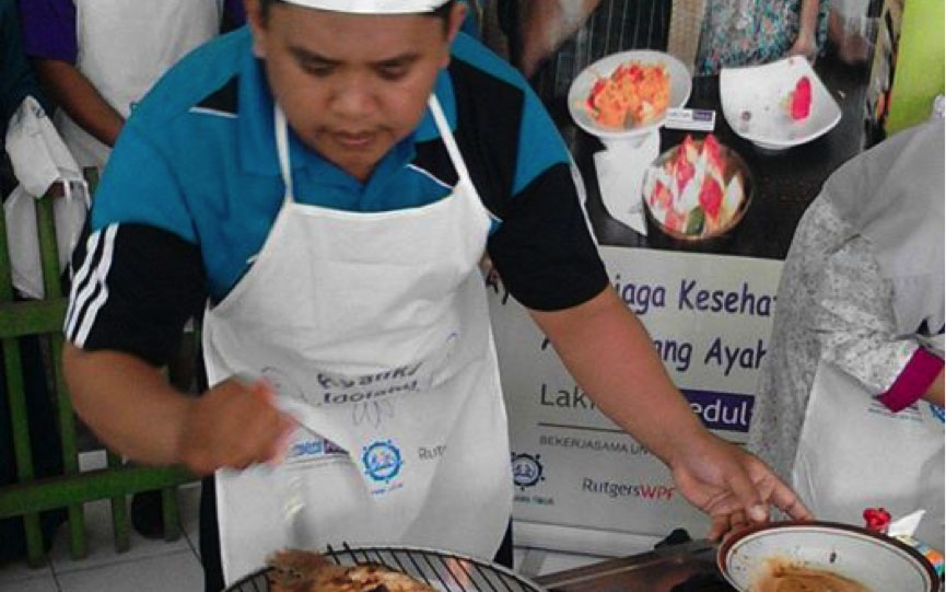 An action shot of a participant from "Cooking Competition for Dads" in indonesia grilling a piece of chicken.