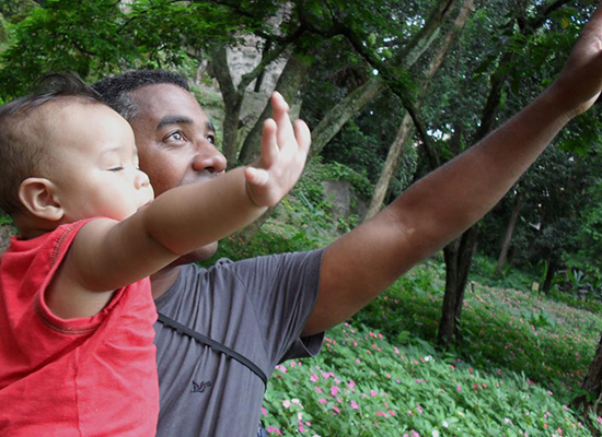 Marcio, a father in Brazil, holds his son as they both reach for the sky