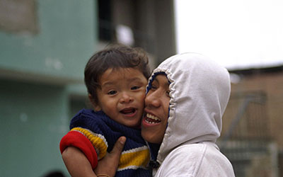 A joyful father holds his smiling, toddler son close in Peru.