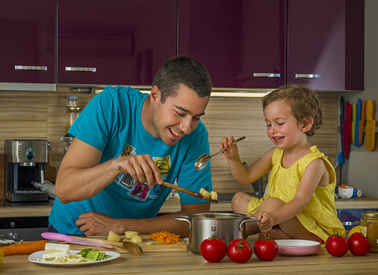 A father cooks with his young daughter