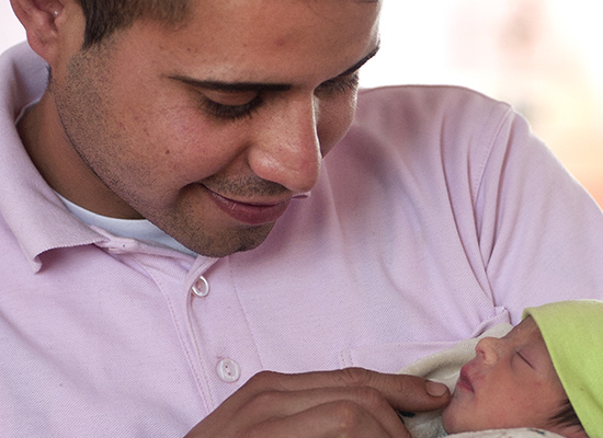 A father holds and smiles at his infant in Chile