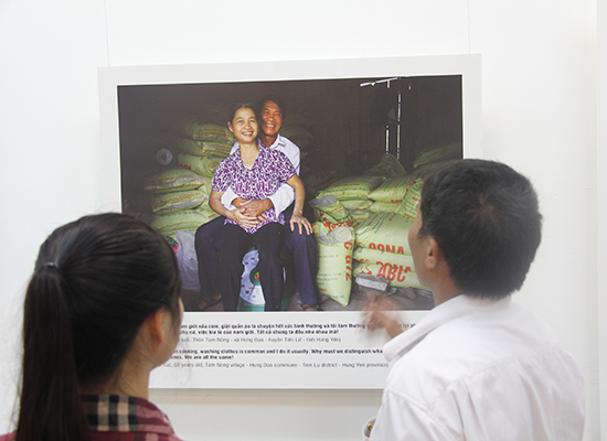 A man and woman look at a photo at an exhibition on nonviolent masculnity in Vietnam