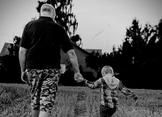 A father holds his young son's hand as they walk together