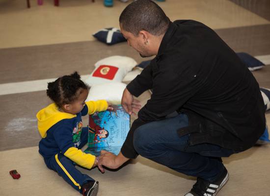 A father helps his young child read a book at Mosaic's "Father and Child Day."