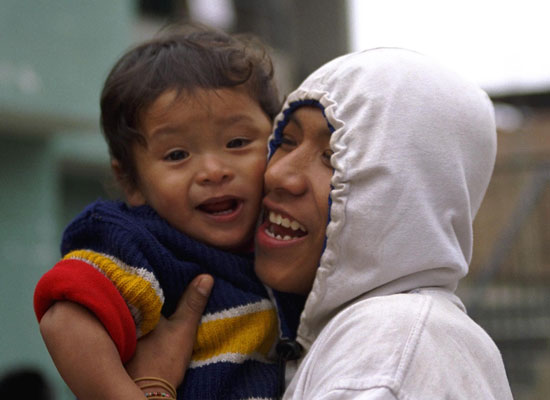 A joyful father holds his smiling, toddler son close in Peru.