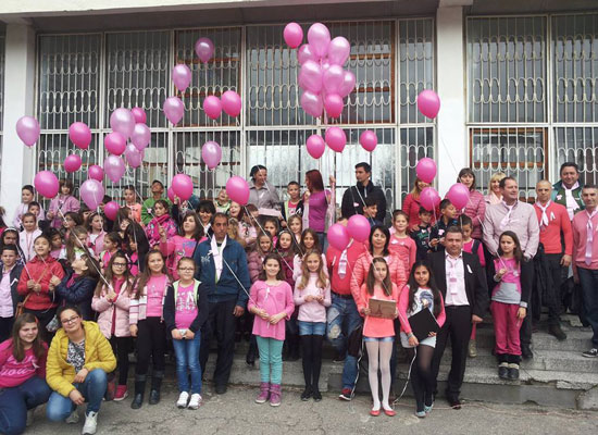 Children and adults dressed in pink hold pink balloons.