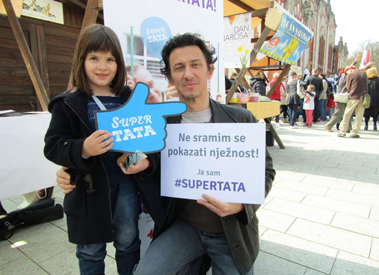 A father holds a sign that reads: "I am not ashamed to show tenderness."