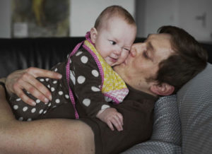 A father holds a baby. Photo: Johan Bävman / mencare.swiss.