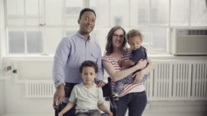 A man, a woman, and two children look at the camera in a still from "America's Dads."