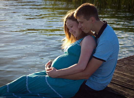 A man embraces his pregnant partner.